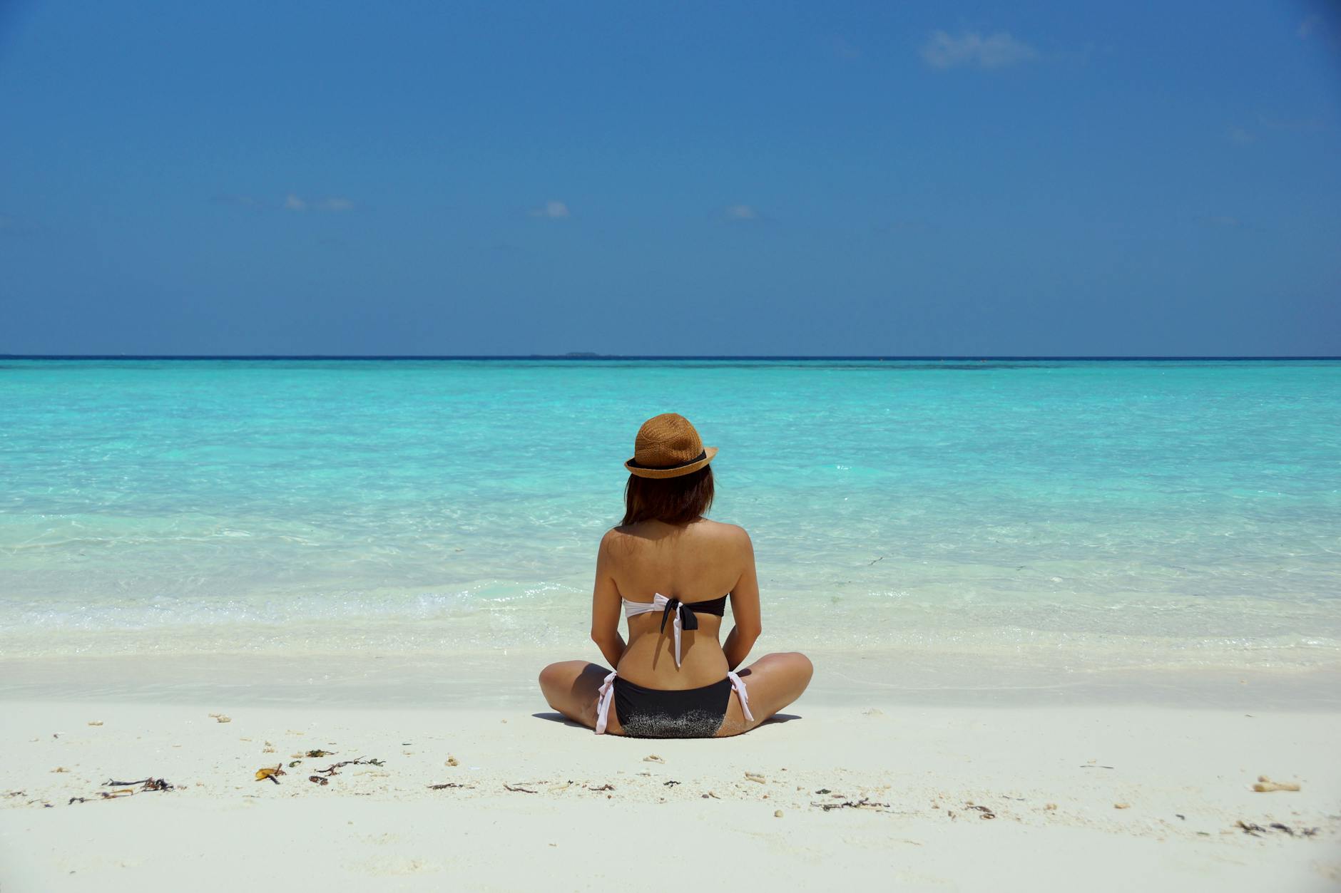 woman wearing black and white bathing suit sitting on white sand